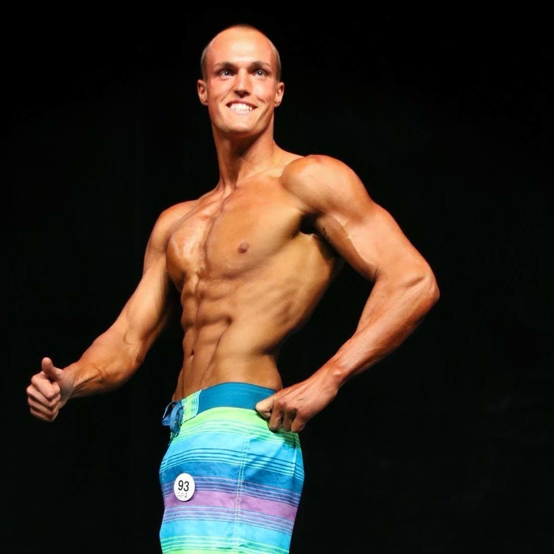A young, lean Mitchell Hooper posing at a physique competition